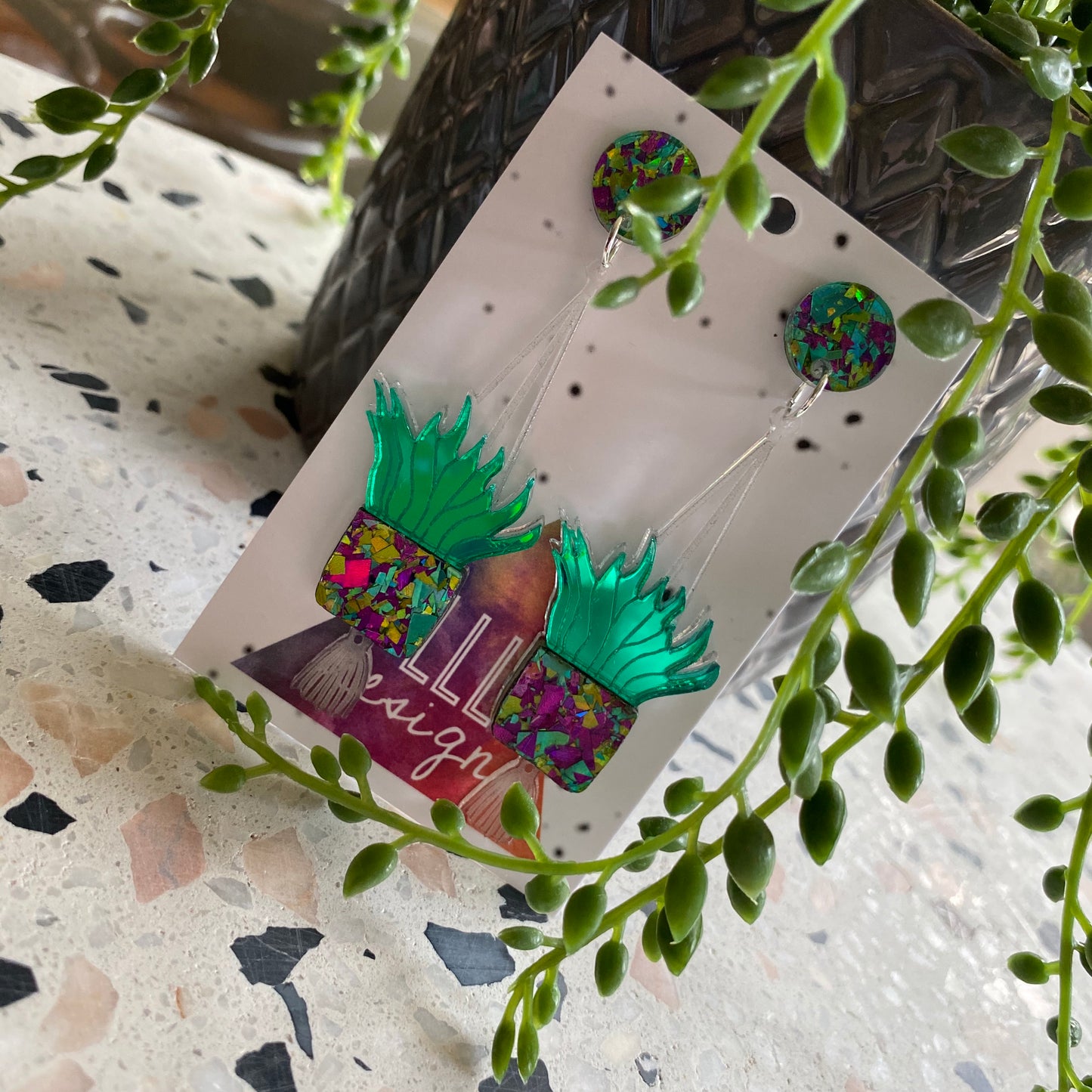 Hanging Planter Dangle Earrings. Featuring Stunning Purple and Green Holographic Planters Hung from Matching Circular Tops.