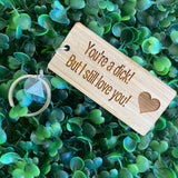 "You're a dick! But I still love you!" Quirky Timber Keyring - Laser Cut & Etched on Timber with Silvertone Hardware finished with a LLL Logo Tag.