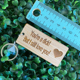 "You're a dick! But I still love you!" Quirky Timber Keyring - Laser Cut & Etched on Timber with Silvertone Hardware finished with a LLL Logo Tag.