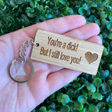 "You're a dick! But I still love you!" Quirky Timber Keyring - Laser Cut & Etched on Timber with Silvertone Hardware finished with a LLL Logo Tag.