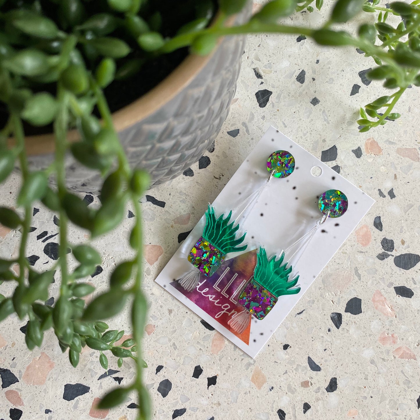 Hanging Planter Dangle Earrings. Featuring Stunning Purple and Green Holographic Planters Hung from Matching Circular Tops.